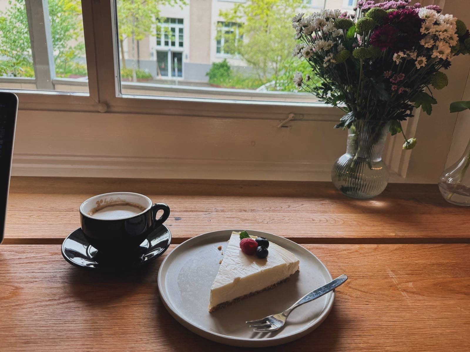 Cappuccino und hausgemachter Cheesecake am Fenster
